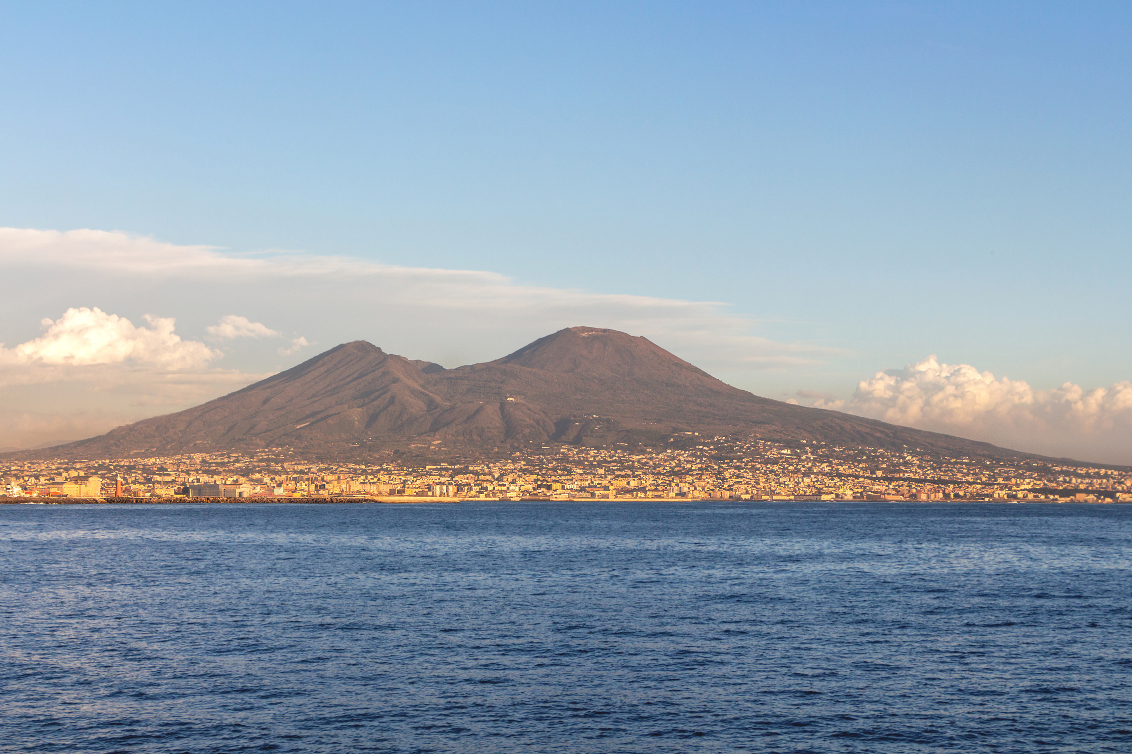 Vesuvius volcano with seashore clouds and city buildings